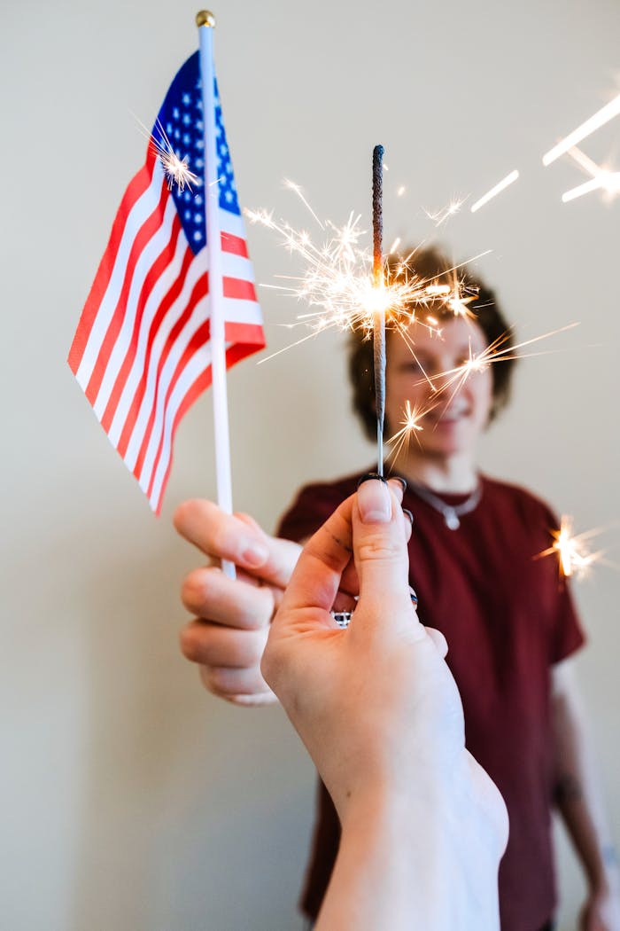 Two people celebrating Independence Day with sparklers and an American flag.