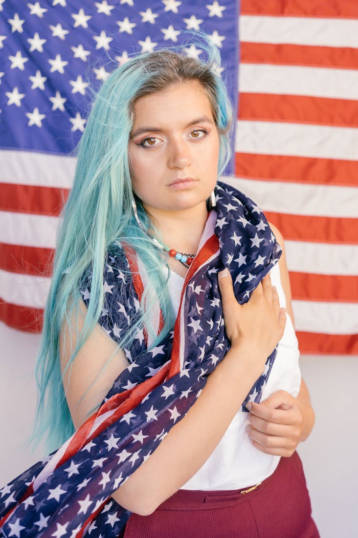 Woman with vibrant hair holding the American flag, showcasing patriotism.